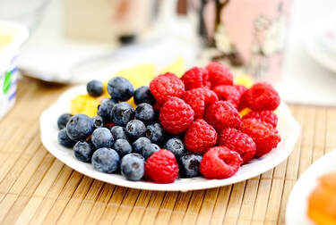 A bright and beautiful picture of a plate of blueberries and raspberries.