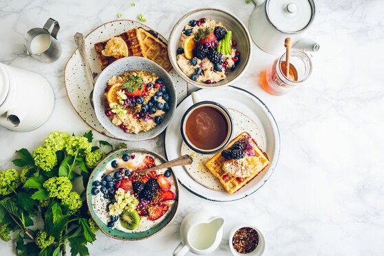 A beautiful picture of healthy nutritious breakfast. Oatmeal and berries, cup of tea, honey, waffles and other fruits. 