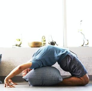 A picture of man bending backwards while kneeling on the floor. This is a yoga pose.
