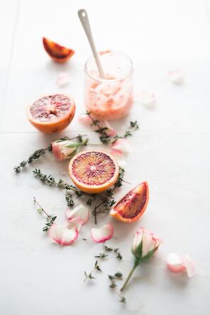 Picture of a glass half filled with smoothie and sliced passionfruit on a table.
